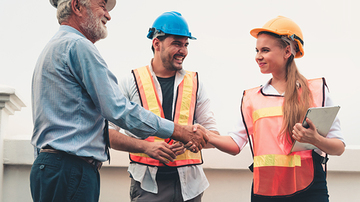 Group of colleagues having a meeting, two people are standing up to shake hands